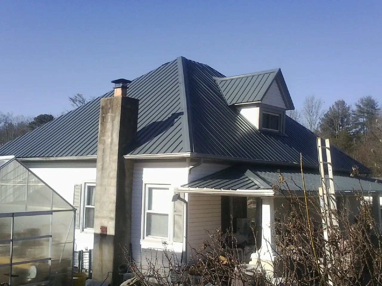 Dark blue standing seam metal roof on a white farmhouse with dormer — Slate & Tile Roof Repair by Roofing Brothers in Effort