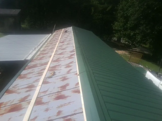 Old rusted panels beside newly installed green metal roofing — Wind Damage Roof Repair by Roofing Brothers in Effort