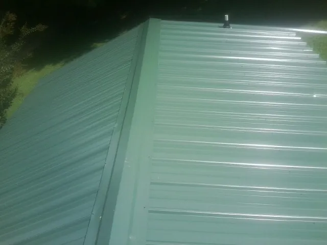New green metal panels meeting at the ridge of a roof — Flat Roof Repair work by our crew in Effort