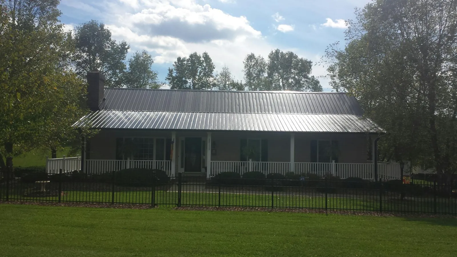 Gray metal roof on a brick ranch with a full width front porch — Gutter Guard Installation work by our crew in Effort