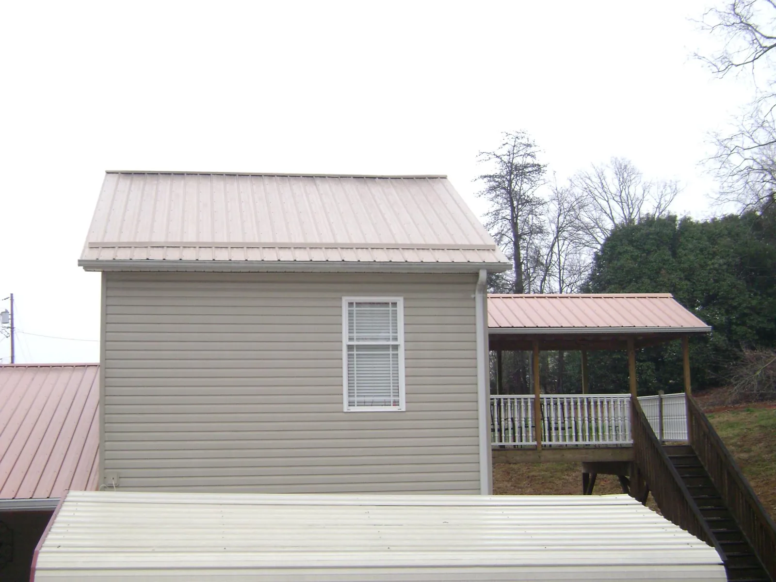 Tan metal roofs on a two story addition and attached porch, from a Roof Replacement job in Effort